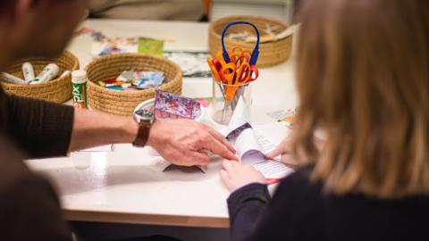 Kuvassa aikuinen ohjaa lasta askartelussa