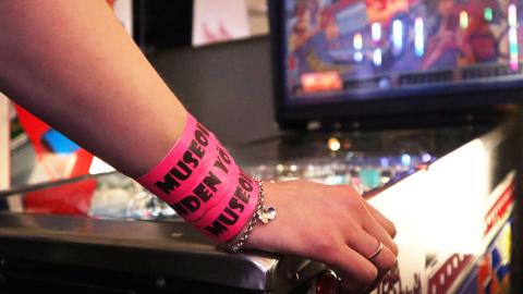 Ranteessa pinkit Museoiden yö -rannekkeet, käsi pelikoneen päällä.