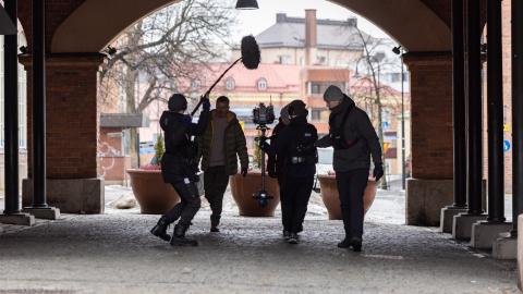 Elokuvan kuvausryhmä kävelee tunnelissa, kaupunki piirtyy taustalla.