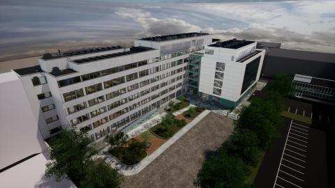 Havainnekuvana ilmakuva, jossa on valkoinen kaksiosainen rakennus. Rakennuksen edessä sisäpiha ja sora-alue.