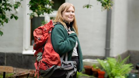 Henkilö rinkan kanssa pihalla.