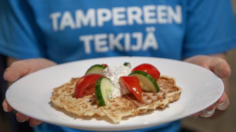 Lautasella vohvelin, jonka päällä on kurkkua ja tomaattia