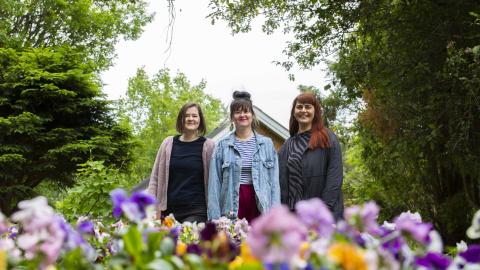  Liisa Aholainen, Janina Ahlfors and Mirjam Larinkari look at the camera from behind the flower beds.