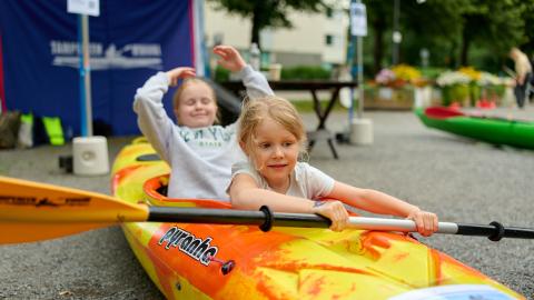 Two children trying out canoeing on a dry land.