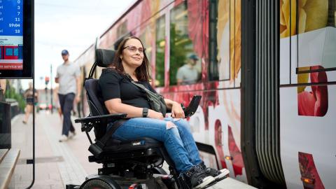 A person in a wheelchair is waiting on the platform to board the tram.