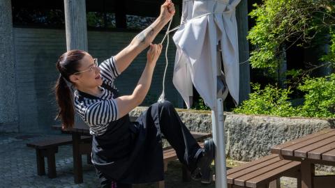 Enni Suihko kiristää aurinkovarjoa ulkona terassilla Cafe Saran edessä.