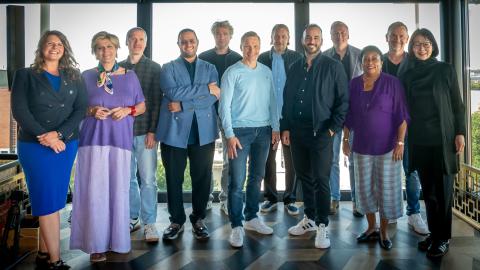 Tuomaristo poseeraa kameralle kuvausseinän edessä.