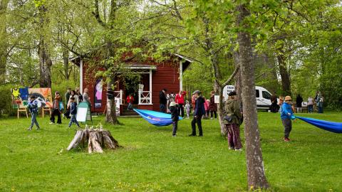 People in a green park with colourful works of art. Some hanging hammocks.