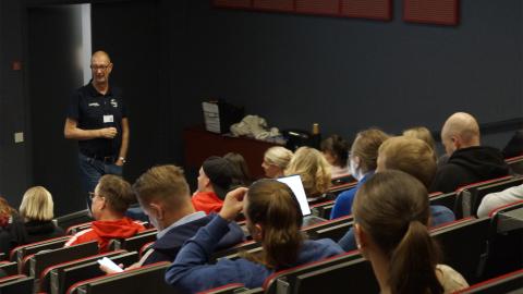 Henkilöitä kuuntelemassa esiintyjän puhetta 