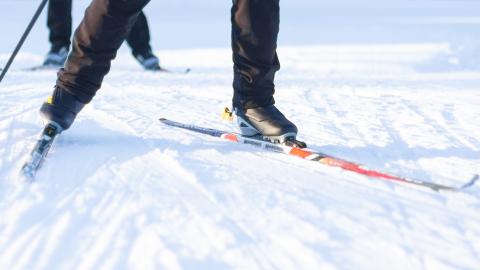 Hiihtäjän sukset aurinkoisella ladulla.