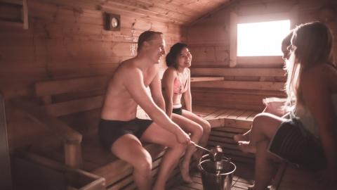 Ihmisiä istumassa saunan lauteilla.