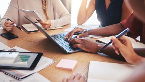 Työtiimi istuu pöydän ympärillä ja pitää kokousta.