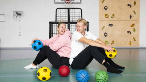 Mustametsän päiväkodin kaksi varhaiskasvatuksen lastenhoitajaa liikuntasalissa.