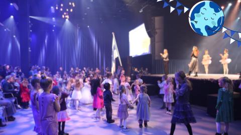 Children dancing in front of the stage. Dance instructors on stage teaching dancing. 