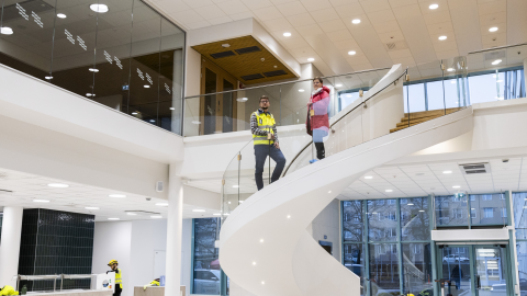 Two people are standing on the curved stairs of the high lobby.