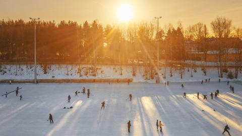 Sorsapuiston ulkojäällä ihmisiä ja laskevan auringon valo. 