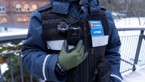 The ticket inspector stands and shows off the body camera on uniform.