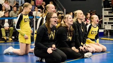 Urheilijoita kannustamssa istuen salin reunalla 