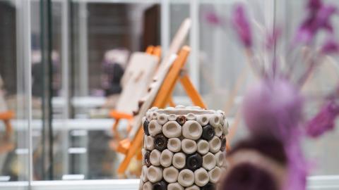 Pottery in a glass display case. In the middle is a pot, and on the side is a piece depicting a figure.