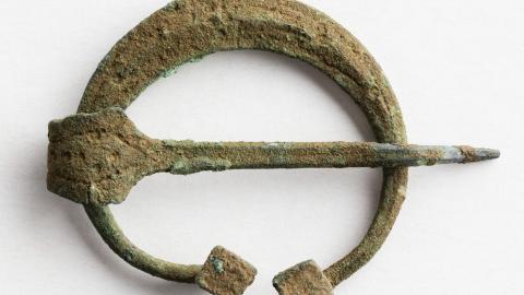 Metallinen puolikuunmuotoinen esine, jonka keskellä on terävä piikki.