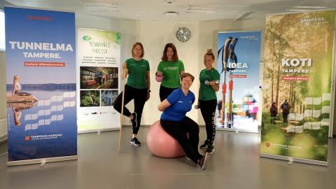 Four smiling women pose with sports equipment.