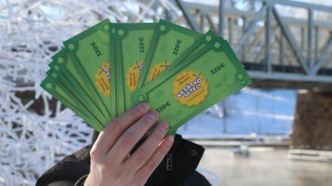 A person is showing summer job vouchers on the banks of the Tammerkoski rapids in winter.