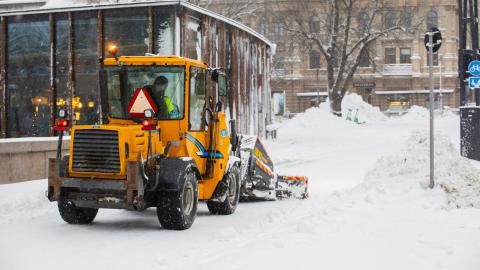 A ploughing tractor works in the centre photographed from behind.