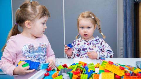Two children are playing with Lego bricks.