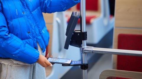 Matkustaja näyttää mobiililippunsa ratikan lukulaitteelle.