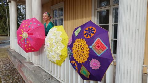Colorful umbrellas decorated with lace are attached to the exterior railing of the manor house.