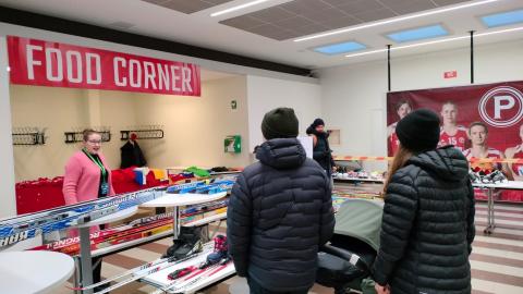 Pariskunta lastenvaunuineen katselee suksia SporttiSwap-tapahtumassa.