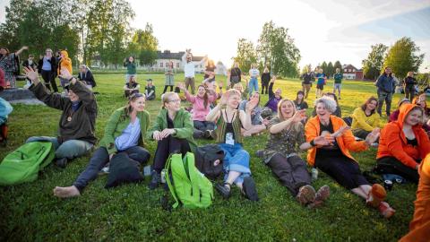 Excited, happy adults in the evening sun sitting on the grass.
