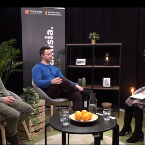 Kaksi miestä ja nainen juttelevat studiossa