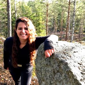 Catherine Ghersi leans to a big stone in the middle of the forest