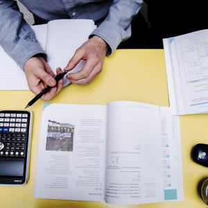A student sitting at a desk studying with books and a calculator.