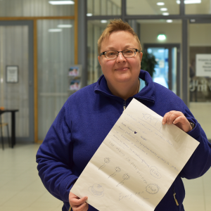 A person is standing in the lobby. They are holding a poster.