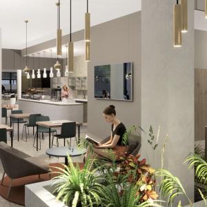 Havainnekuva kahvilan pöydistä ja etualalla olevasta kasvialtaasta, joka kiertää pylvästä.