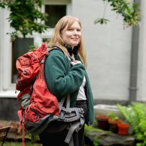 Henkilö rinkan kanssa pihalla.