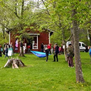 People in a green park with colourful works of art. Some hanging hammocks.