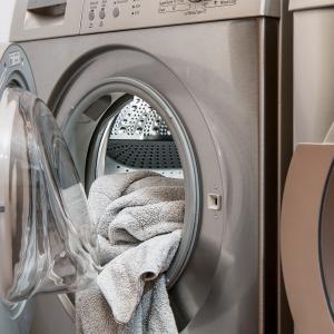 Pyykkikoneeseen on menossa pyyhepyykki, vieressä myös teräksinen kuivausrumpu.