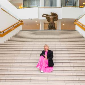 Henkilö istuu portailla. Taustalla ylätasanteella on patsas.