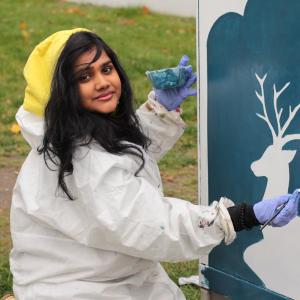 Nuori nainen maalaa sähkökaappia Etelä-Hervannassa.