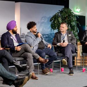 Growth with international talent -forum. Five panelists speak on stage at the forum.