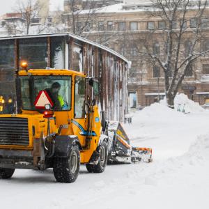 A ploughing tractor works in the centre photographed from behind.