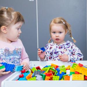 Two children are playing with Lego bricks.