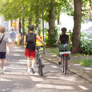 Kävelijöitä ja pyöräilijöitä Tampereen keskustassa, taustalla pysäköityjä autoja.