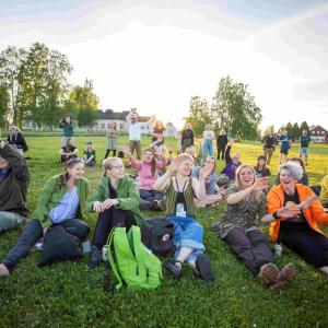 Excited, happy adults in the evening sun sitting on the grass.