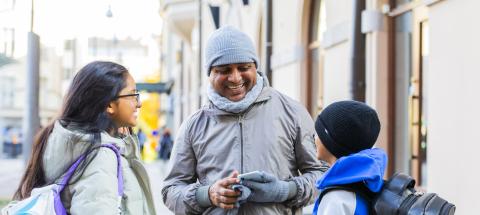 Kaksi aikuista ja lapsi juttelevat kadulla.
