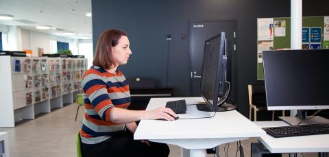 Asiakas tietokoneella Tesoman kirjastossa.