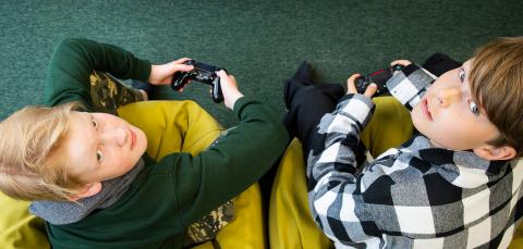 Kaksi poikaa pelaa Playstationilla.